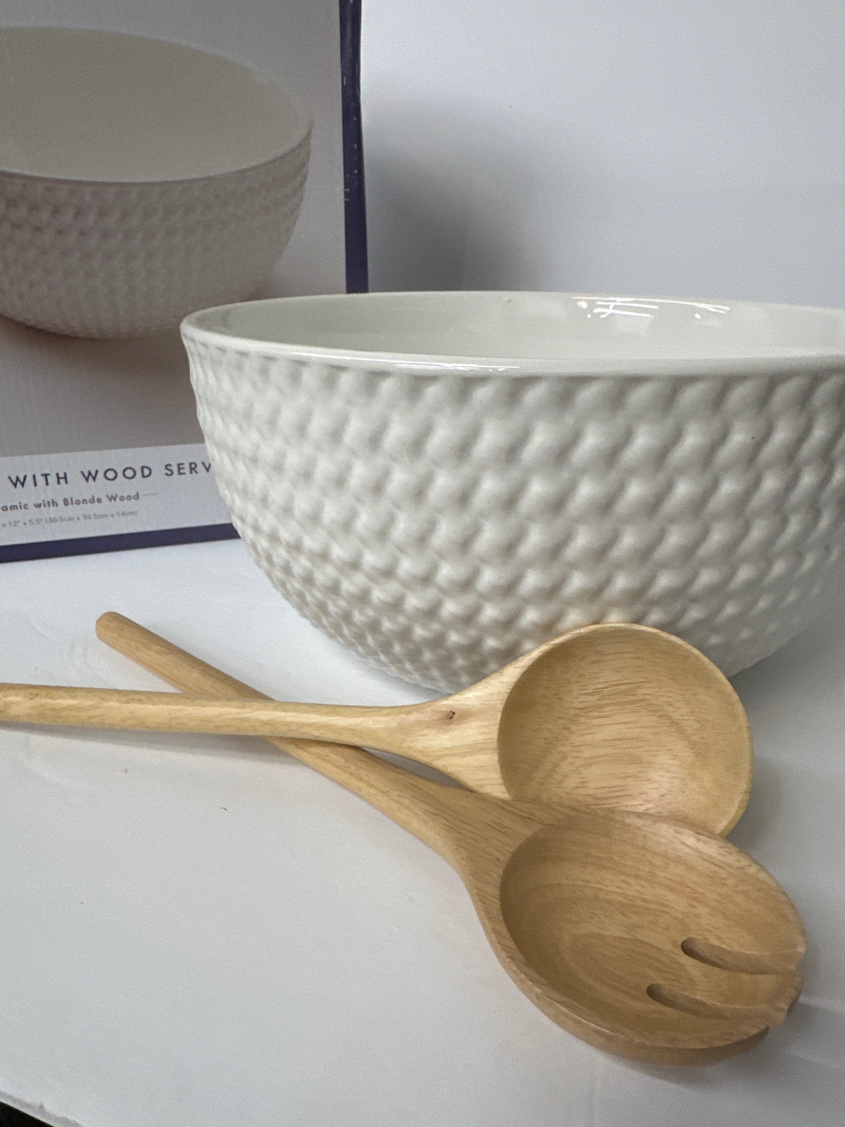 White salad bowl with wooden server utensils