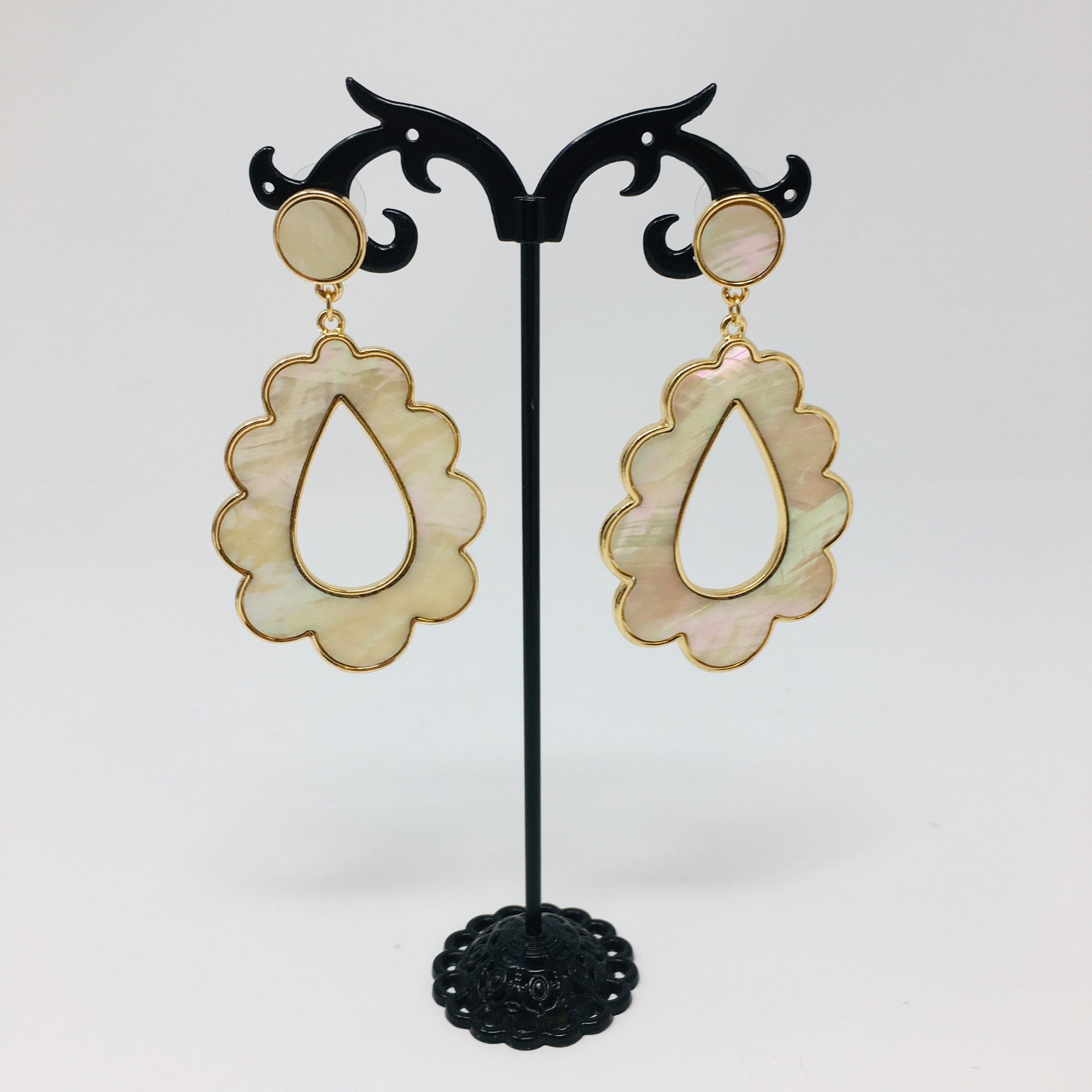Scalloped teardrop shaped gold tone earrings with mother of pearl inserts shown on a white background