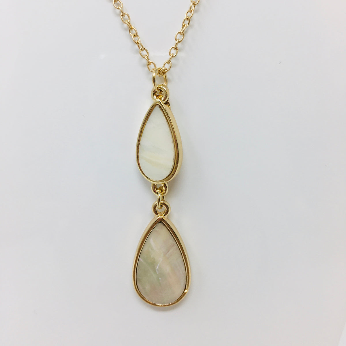 close up view of double teardrop pendant with mother of pearl inserts in the teardrops shown on white background