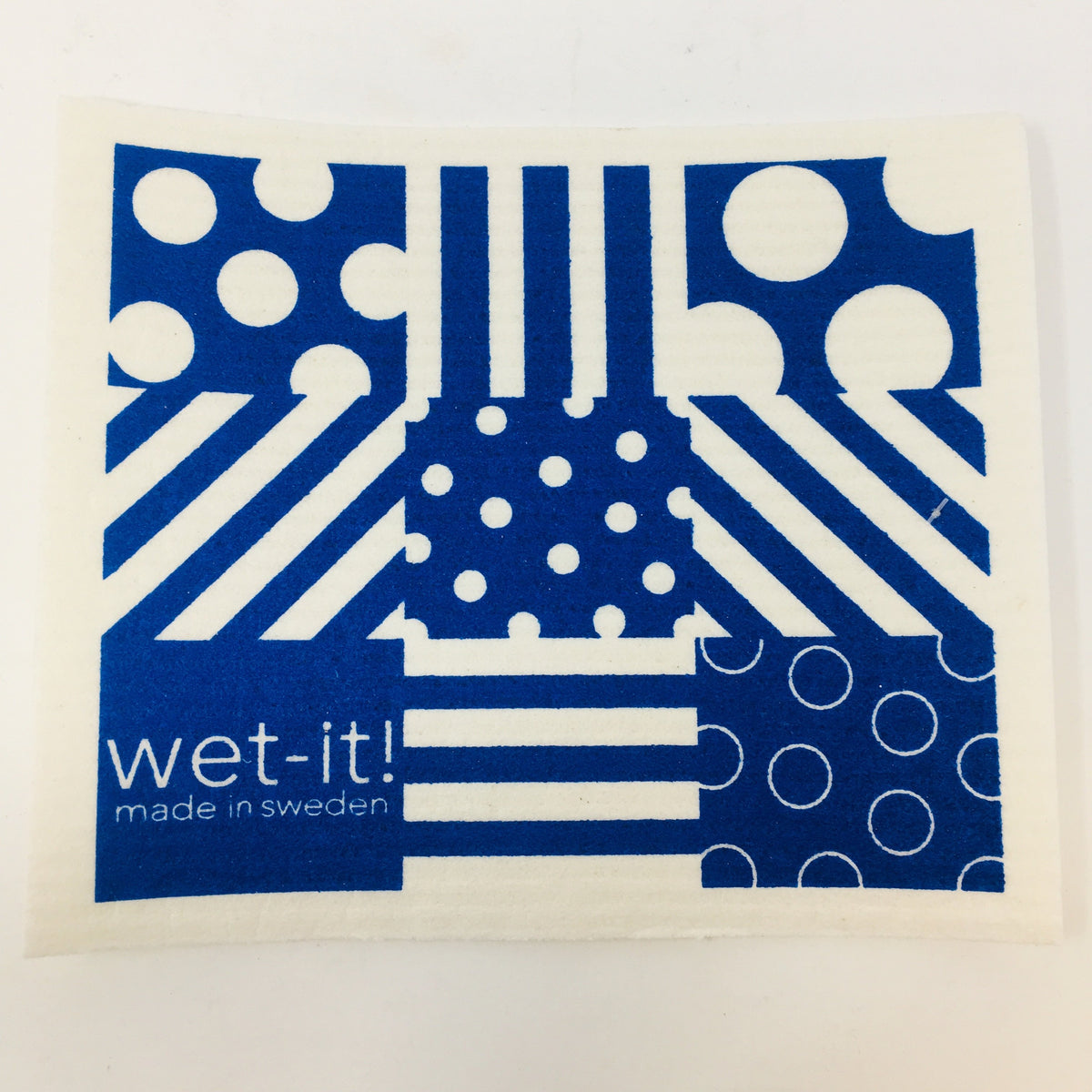 ivory colored rectangle shaped scrubbing pad with a blue patchwork pattern of stripes and dots in blue screen printed on it