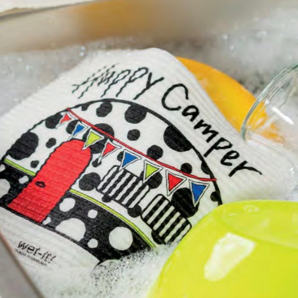 Happy Camper patterned Wet-it towel laying in a sink of soap suds with dishes to be washed