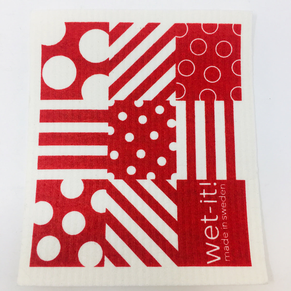 ivory colored rectangle shaped scrubbing pad with a blue patchwork pattern of stripes and dots in red screen printed on it