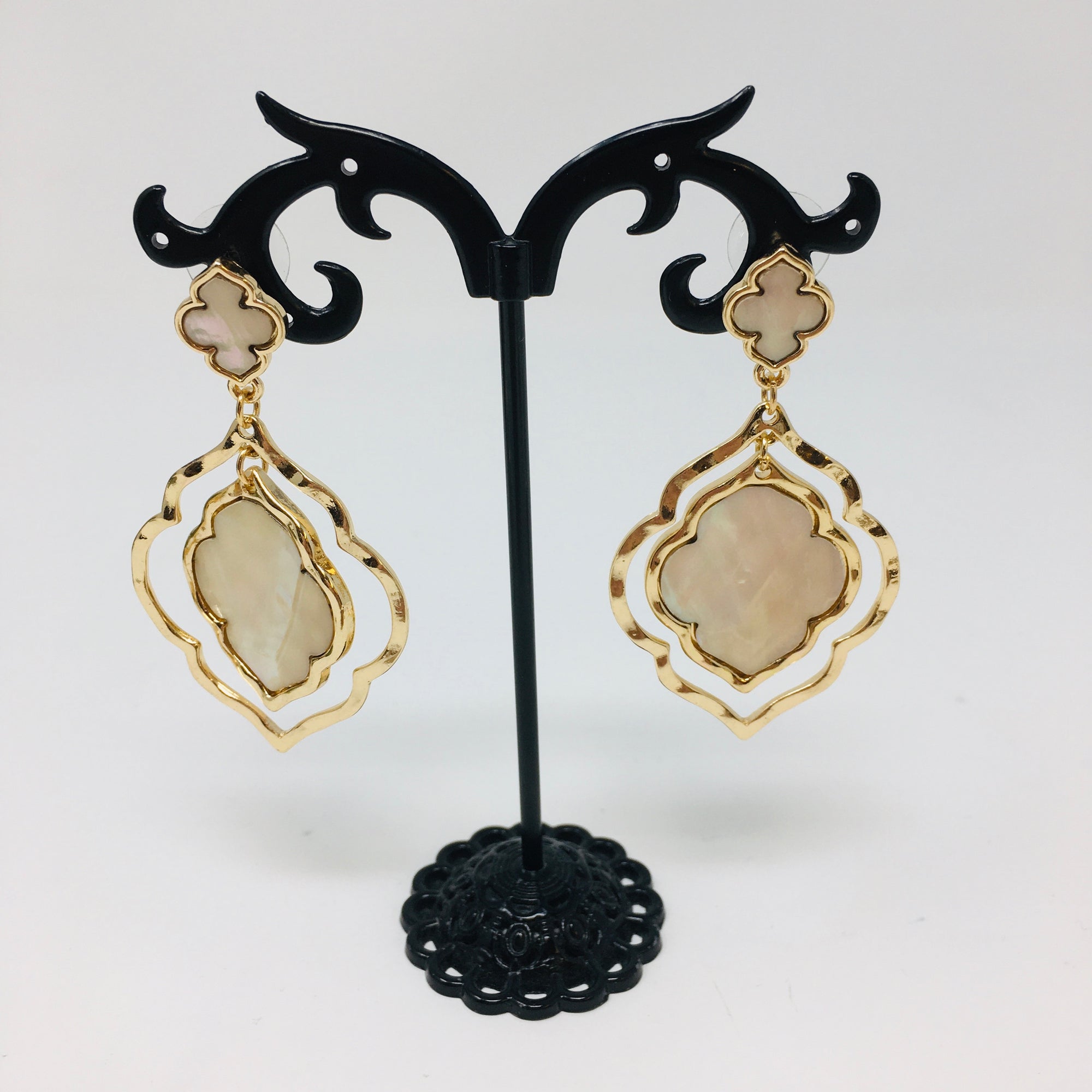double layer arabesque shaped gold tone earrings with mother of pearl inserts shown on a white background
